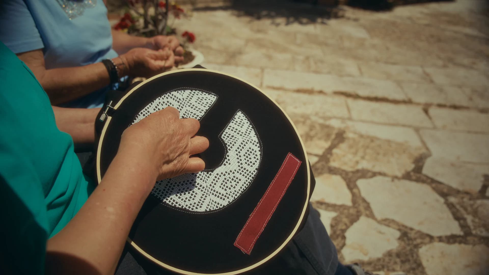 Hands turning a circular game piece in a sunlit stone courtyard