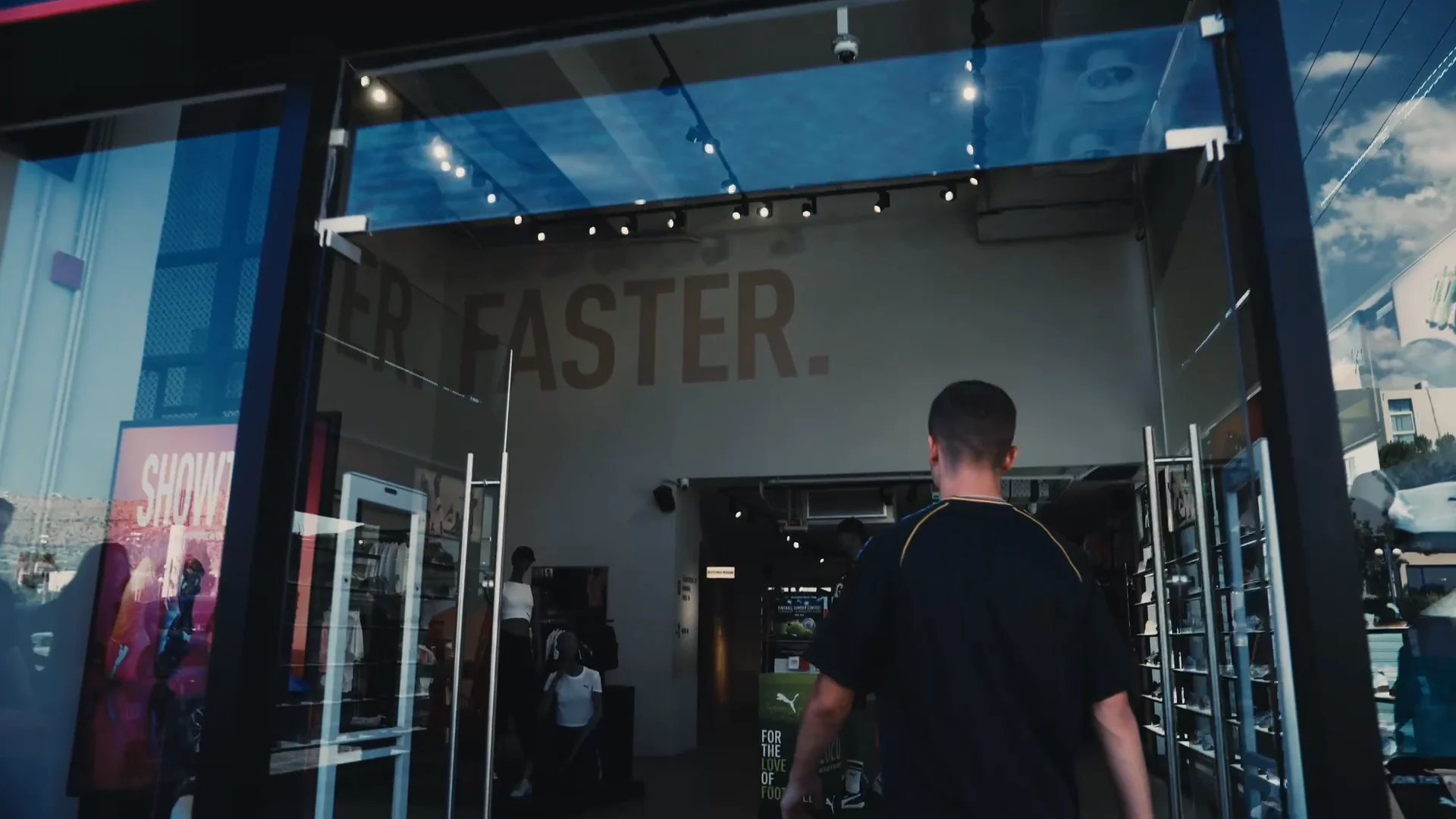 Mouzakitis walking through the glass entrance of the sports store