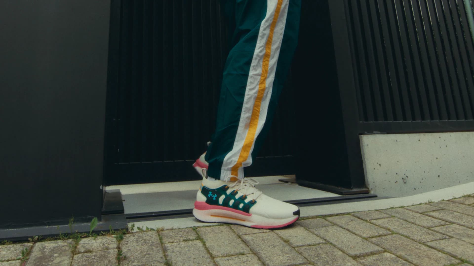 Custom Under Armour shoe stepping past a dark studio wall