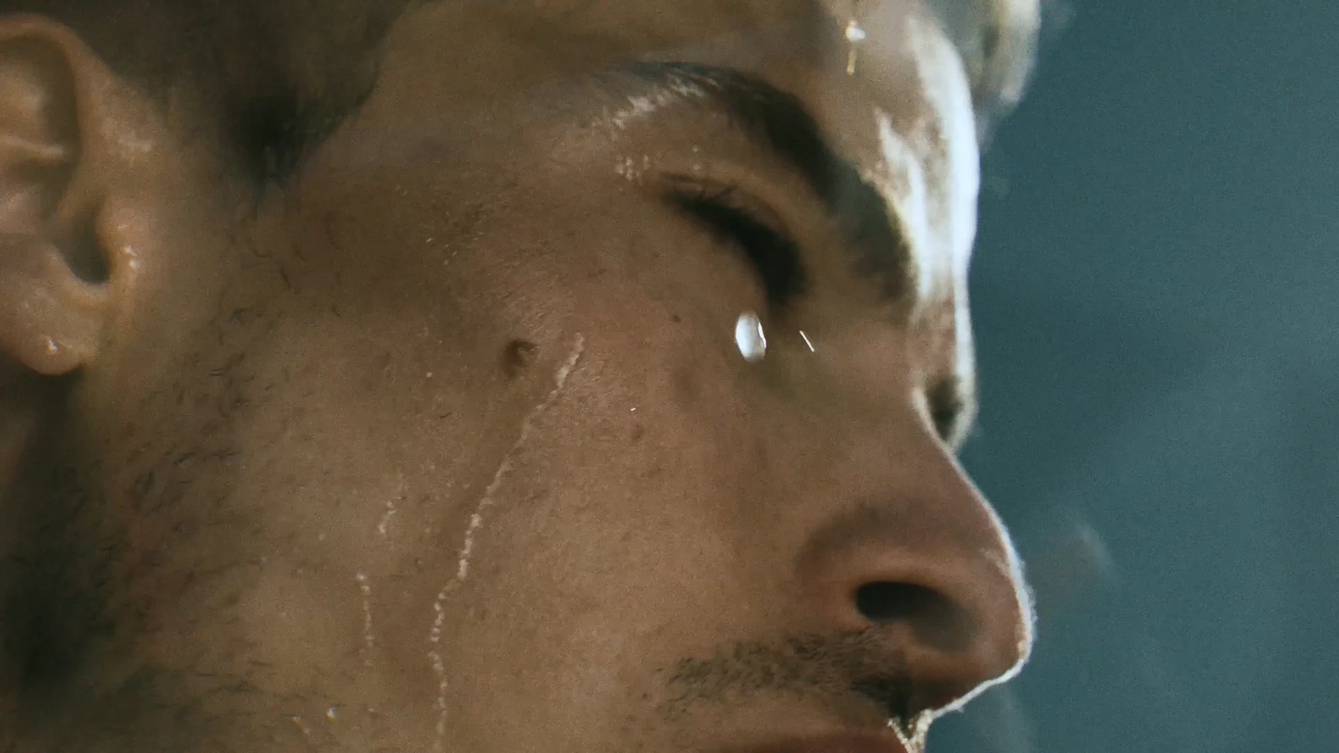 Close-up of a runner's face beaded with sweat in cold light